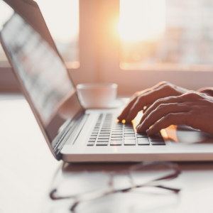 Hands typing on open laptop